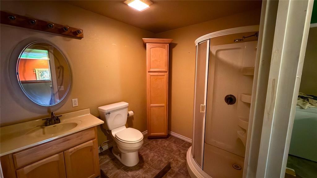 2900 Robinson Road Denton, TX 76210 - Photo 20 of 33 Bathroom featuring a corner shower enclosure, a wood-finish vanity with an integrated sink, a toilet, a tall storage cabinet, and tiled flooring
