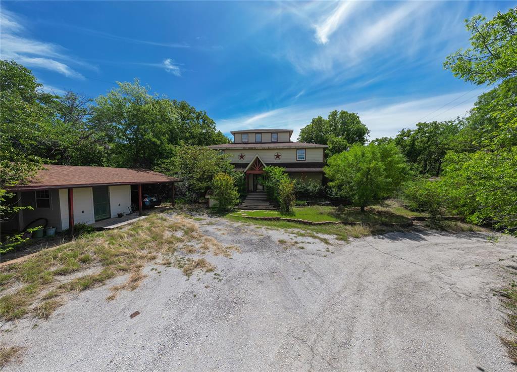 2900 Robinson Road Denton, TX 76210 - Photo 3 of 33 Terraced property featuring a multi-story main residence with a prominent entryway, a detached single-story structure with an extended covered area, and a substantial gravel and paved driveway