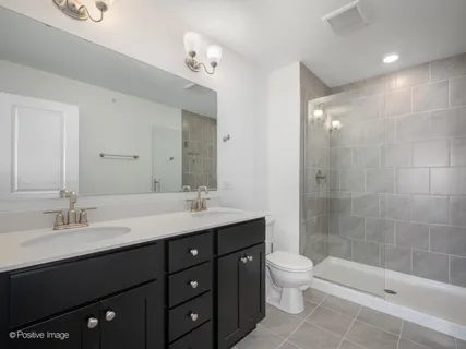 a bathroom with a double vanity sink toilet and shower
