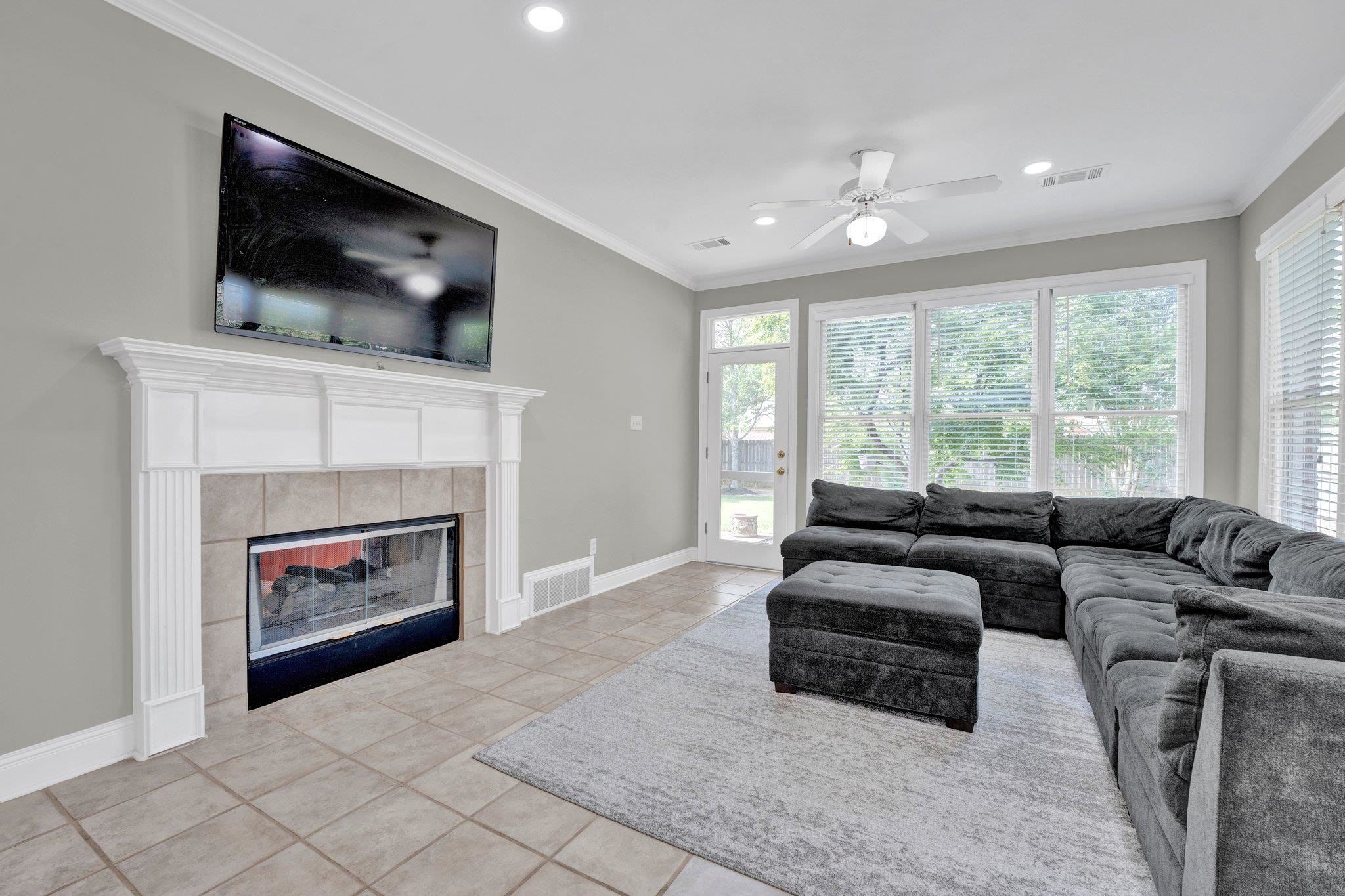 1331 Riding Brook Drive Collierville, TN 38017 - Photo 11 of 39 Living room featuring light tile patterned flooring, a fireplace, crown molding, and ceiling fan