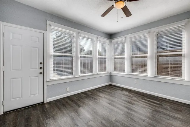 an empty room with wooden floor and windows