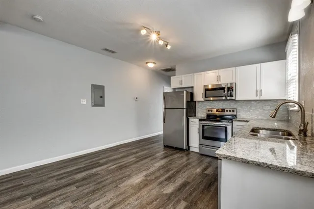 a kitchen with stainless steel appliances granite countertop a refrigerator a stove top oven a sink and dishwasher