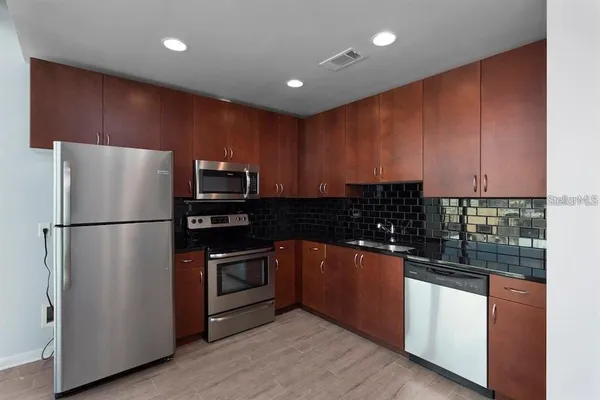 a kitchen with stainless steel appliances granite countertop a refrigerator and a stove