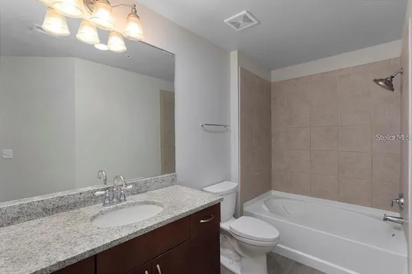 a bathroom with a granite countertop sink a toilet and a mirror