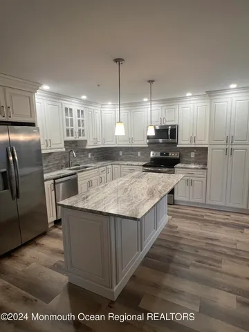 a large kitchen with stainless steel appliances granite countertop a stove a sink and a refrigerator