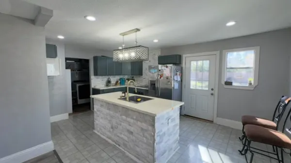 a large kitchen with a refrigerator a sink dishwasher a stove and a dining table with wooden floor