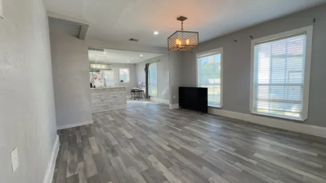 a view of an empty room with wooden floor and a window