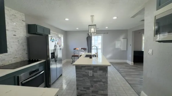 a large kitchen with stainless steel appliances a large counter top a stove and a refrigerator