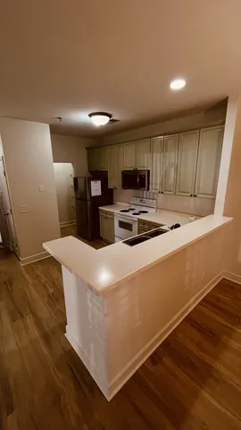 a kitchen with kitchen island a stove top oven a sink dishwasher and a refrigerator with wooden floor