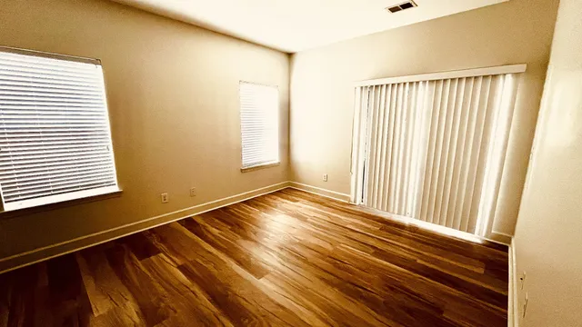 a view of empty room with wooden floor and fan