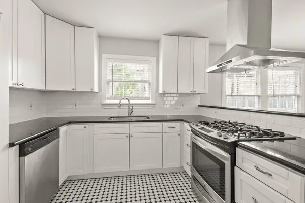 a kitchen with stainless steel appliances granite countertop a stove a sink and a white cabinets