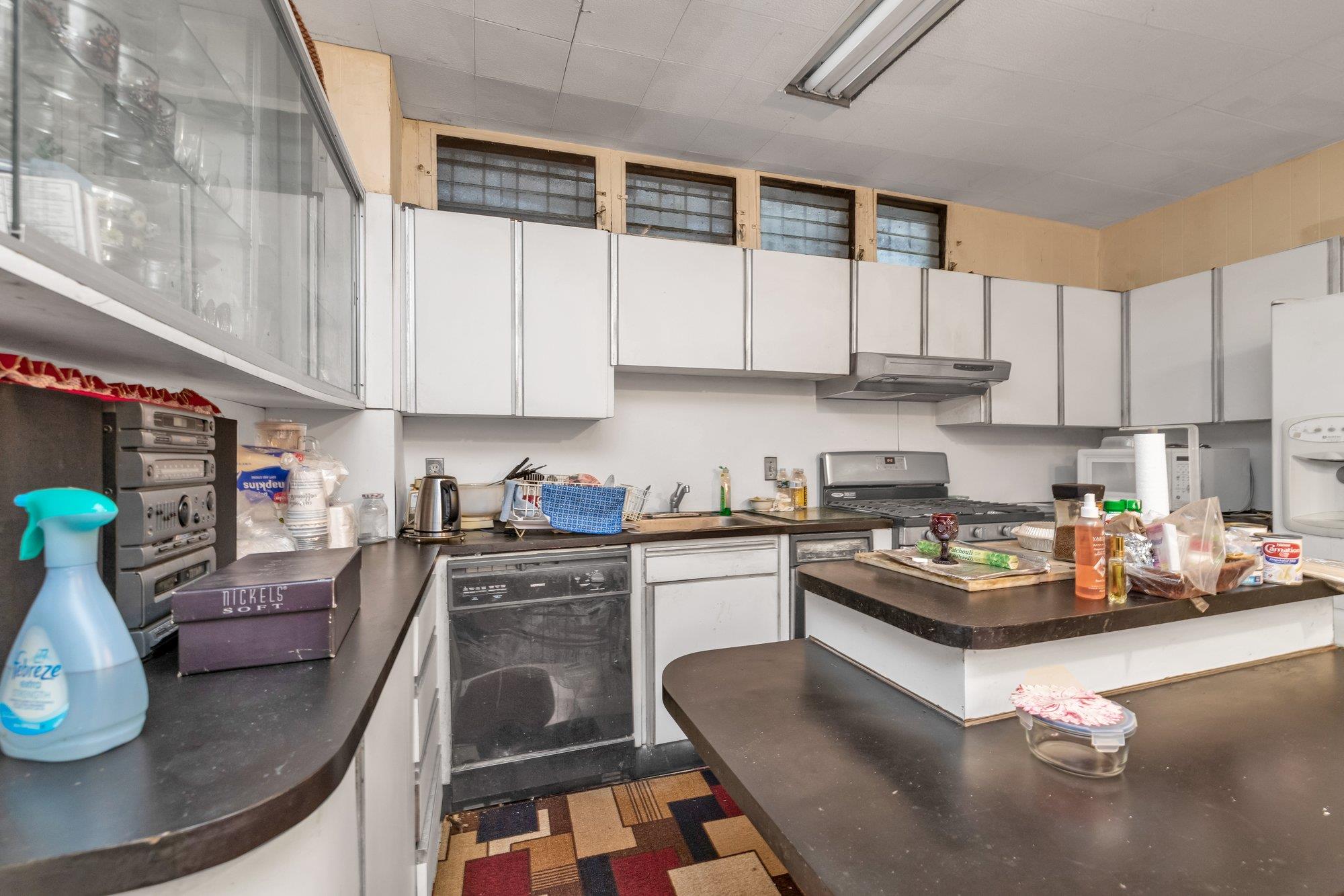 112-50 38th Avenue Queens, NY 11368 - Photo 12 of 17 a kitchen with stainless steel appliances granite countertop a stove a refrigerator a sink a stove and white cabinets