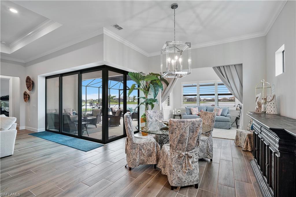 20150 Napa Loop Estero, FL 33928 - Photo 14 of 49 Dining space featuring an inviting chandelier, ornamental molding, hardwood / wood-style flooring, and a raised ceiling
