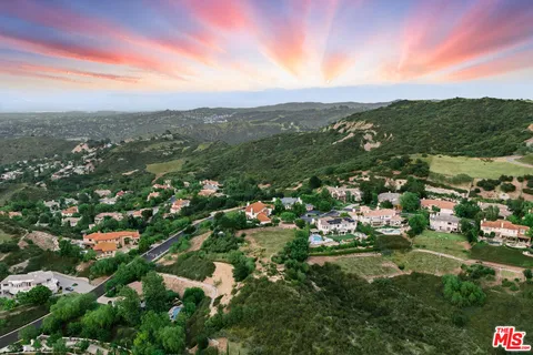 an aerial view of residential houses with outdoor space and trees