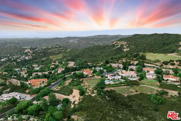an aerial view of residential houses with outdoor space and trees