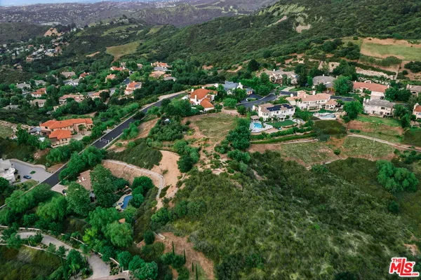 an aerial view of residential houses with outdoor space and trees all around