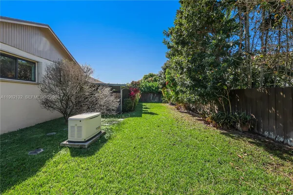 a backyard of a house with table and chairs plants and large tree