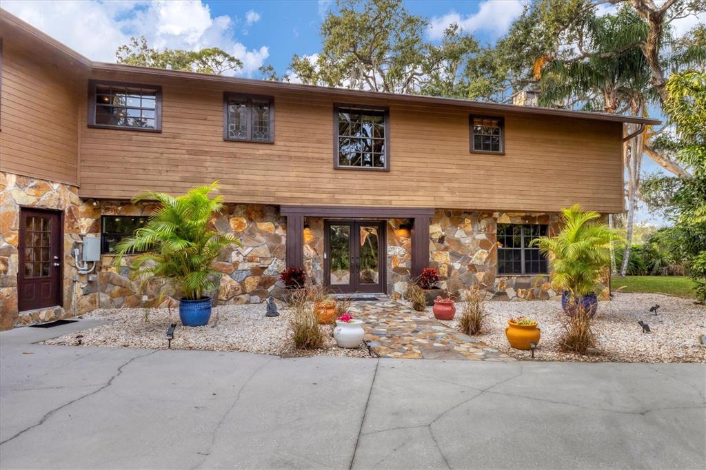 2308 Shadow Oaks Road Sarasota, FL 34240 - Photo 7 of 84 a view of a brick house with potted plants in front of door