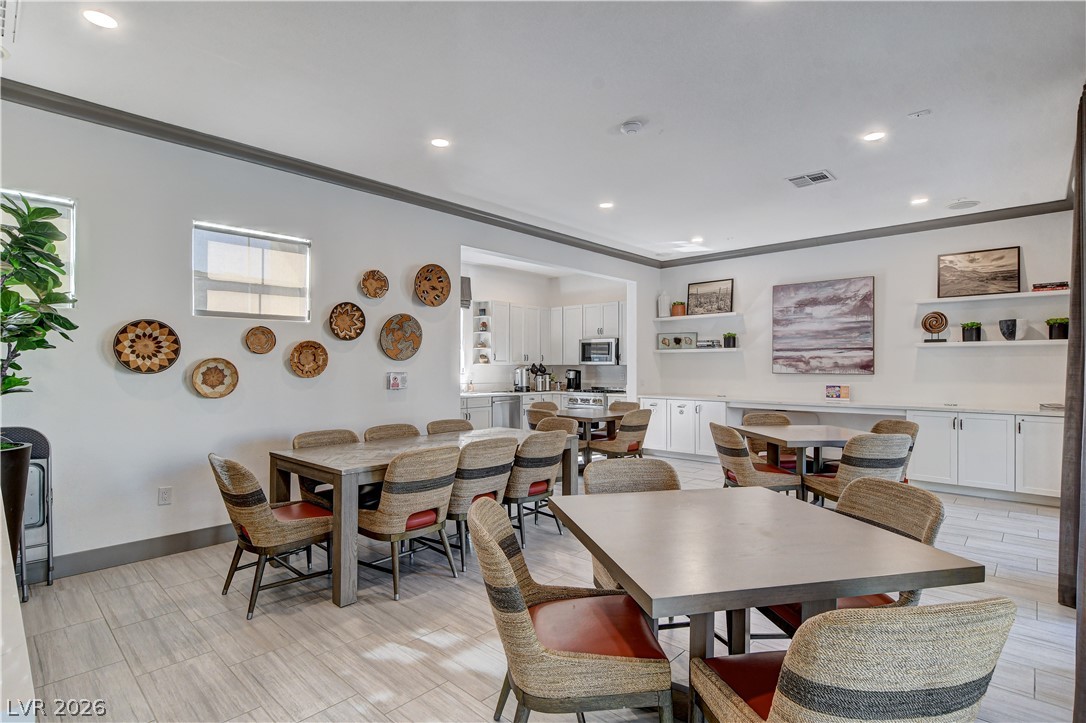 2555 Hampton Road, Unit 2207 Henderson, NV 89052 - Photo 60 of 74 A well-lit common area features multiple dining tables and a convenient kitchen at the rear, ideal for community gatherings.