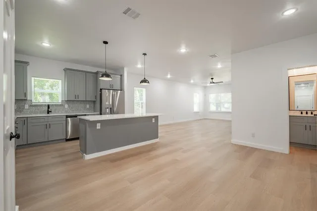 a large kitchen with stainless steel appliances kitchen island a large counter top and a wooden floors