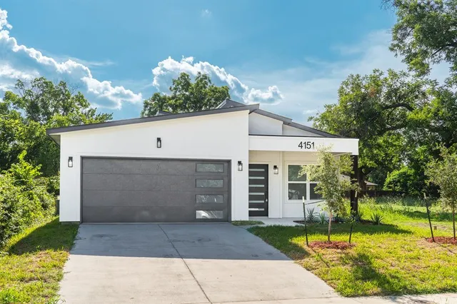 a view of a white house with a yard and potted plants