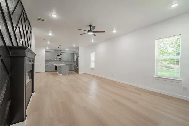 an empty room with chandelier fan and windows