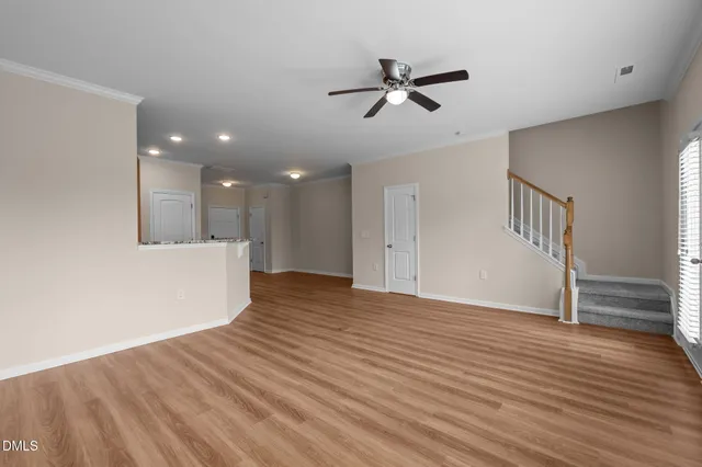 a view of empty room with wooden floor and fan