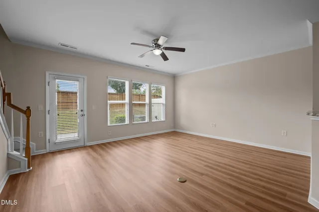 a view of kitchen and empty room with wooden floor