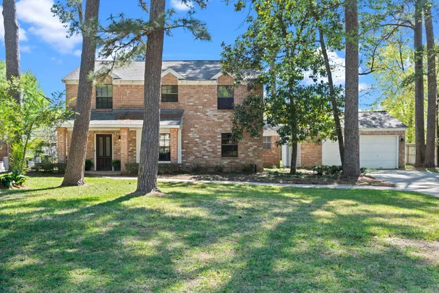 a view of a big yard in front of a brick house with a large tree
