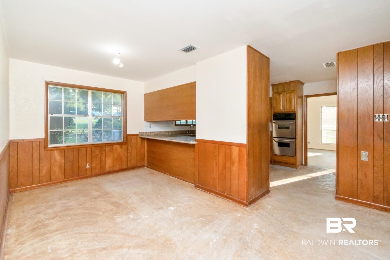 241 Suzanne Circle Mobile, AL 36608 - Photo 8 of 41 Kitchen with brown cabinetry, a wainscoted wall, wood walls, and double oven