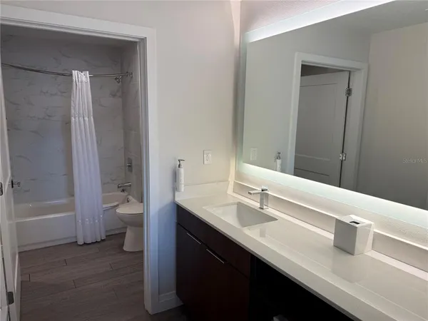 a bathroom with a granite countertop sink a toilet and shower
