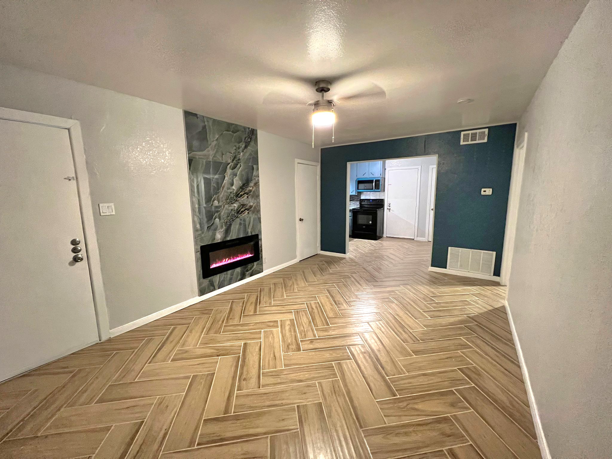 805 Sissom Road Killeen, TX 76541 - Photo 2 of 35 Unfurnished living room with ceiling fan, a fireplace, parquet flooring, and a textured wall