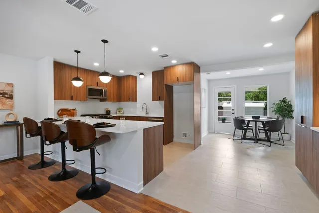 a kitchen with stainless steel appliances granite countertop a stove a sink a refrigerator and chairs