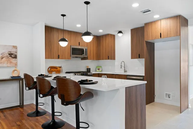 a kitchen with stainless steel appliances granite countertop a stove a refrigerator a sink a dining table and chairs with wooden floor