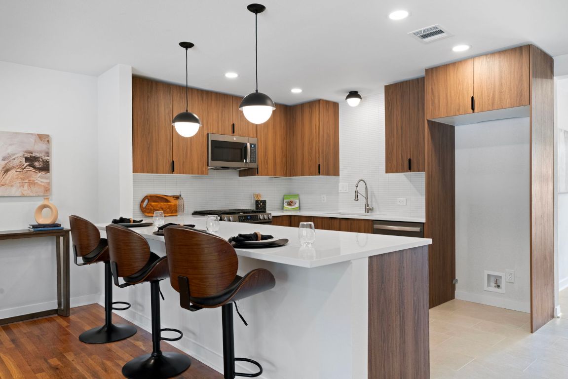 1609 Chatham Avenue Austin, TX 78723 - Photo 2 of 31 a kitchen with stainless steel appliances granite countertop a stove a refrigerator a sink a dining table and chairs with wooden floor