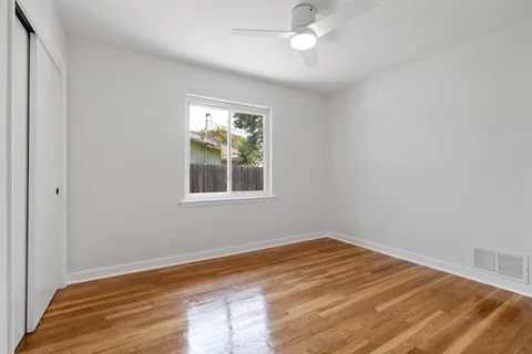 a view of empty room with wooden floor and fan