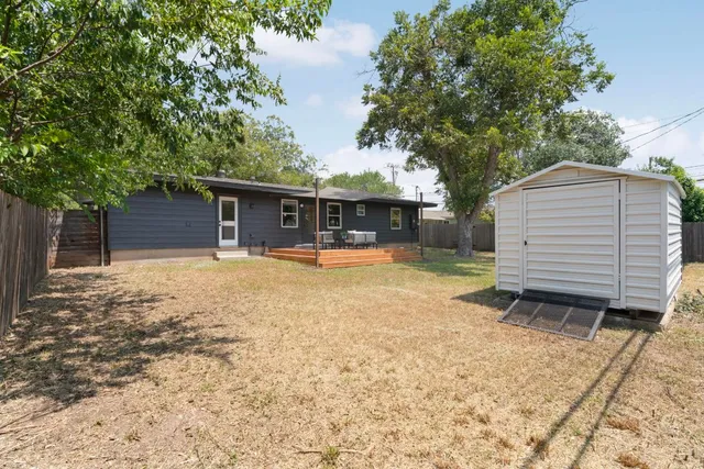 a view of a house with a yard and large tree