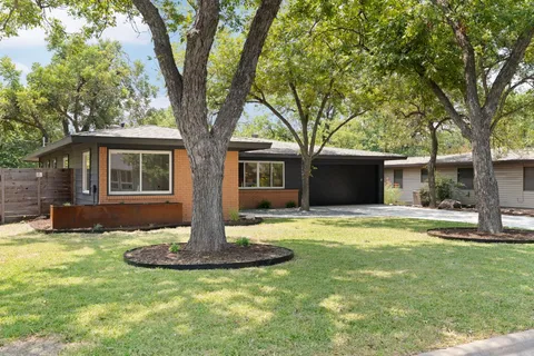 a front view of a house with a garden and trees