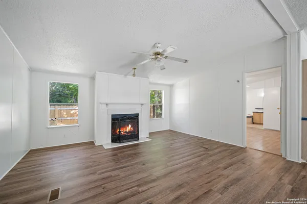 an empty room with windows fireplace and wooden floor