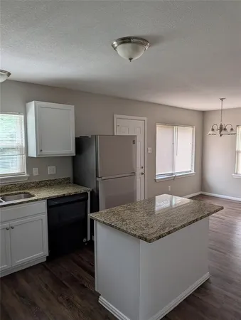 a kitchen with granite countertop a sink stove and refrigerator