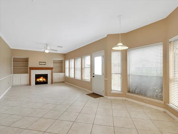 an empty room with windows and fireplace