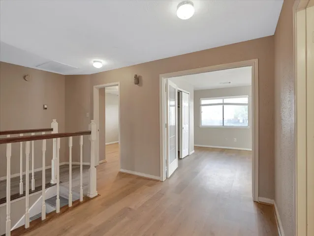 a view of empty room with wooden floor and ceiling fan