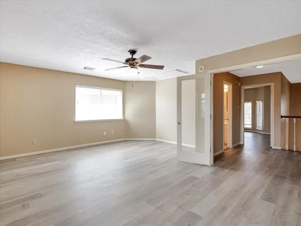 an empty room with wooden floor and windows with curtains