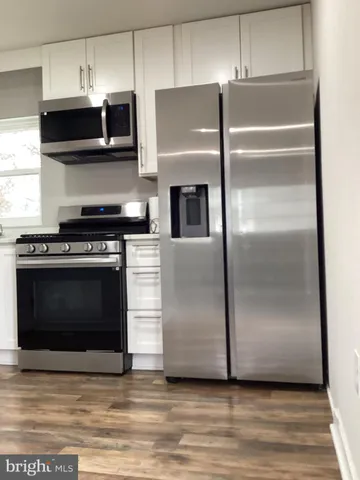 a kitchen with granite countertop a refrigerator and a stove top oven