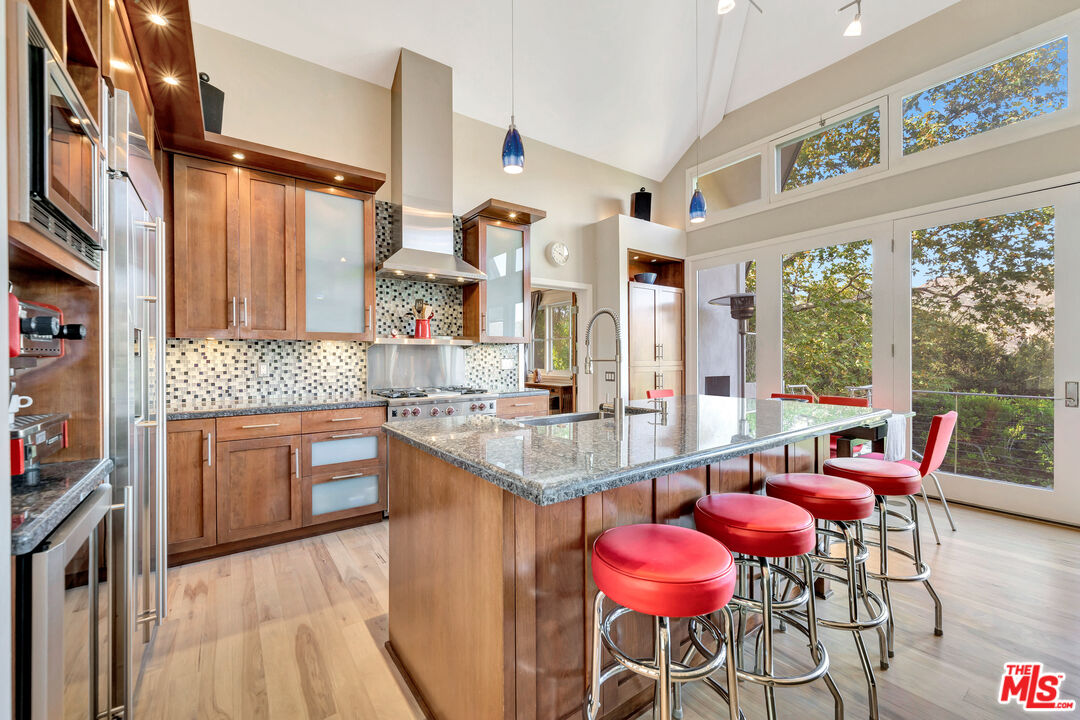 26227 Fairside Road Malibu, CA 90265 - Photo 4 of 30 a kitchen with stainless steel appliances kitchen island granite countertop a dining table chairs and a large window