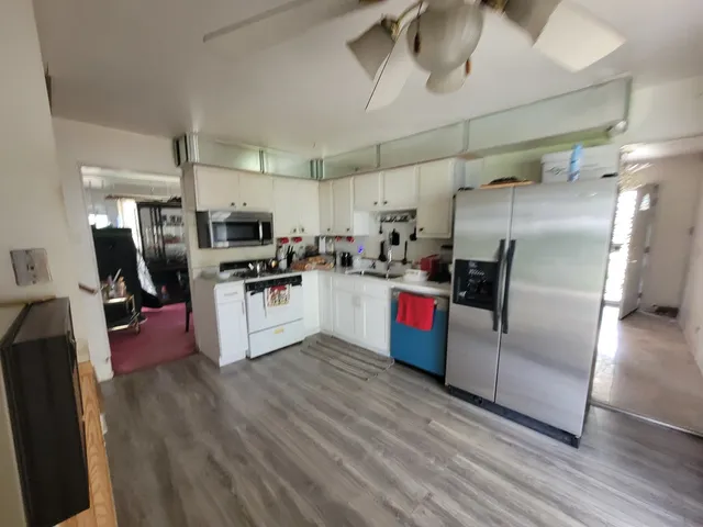 a kitchen with stainless steel appliances a refrigerator a sink a stove and white cabinets