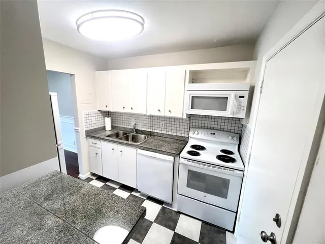 a kitchen with granite countertop a stove sink and cabinets
