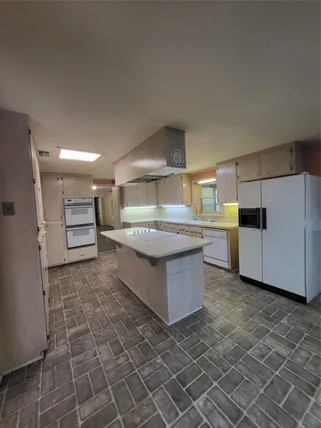 a large kitchen with stainless steel appliances a stove a refrigerator and a cabinets