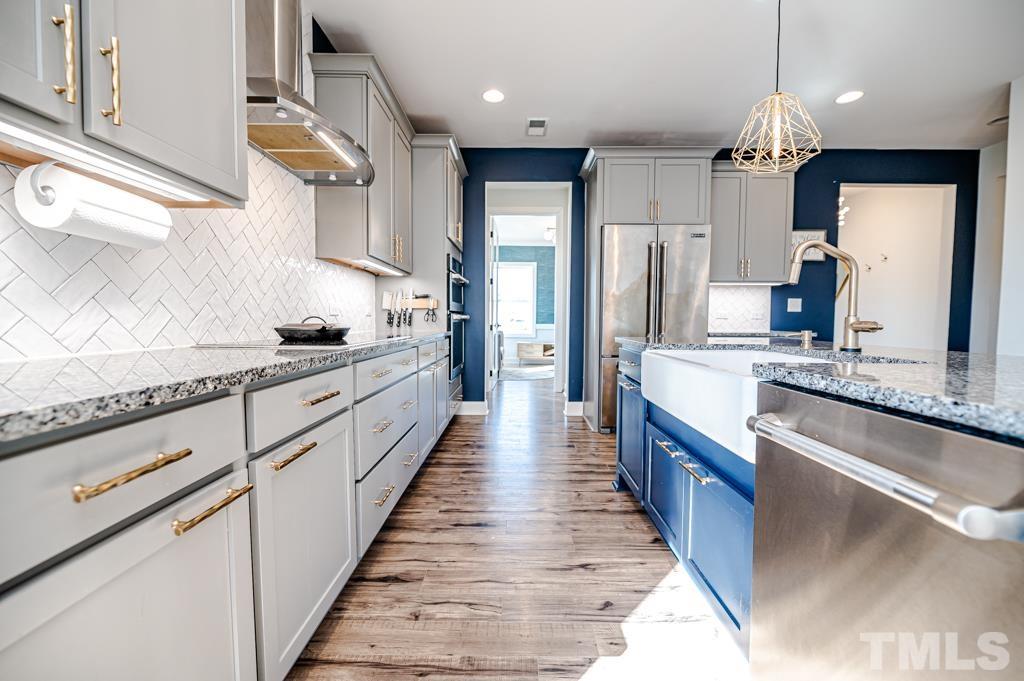 6712 Lucado Court Raleigh, NC 27603 - Photo 16 of 52 a large kitchen with stainless steel appliances kitchen island granite countertop a stove a sink dishwasher and a refrigerator with wooden floor