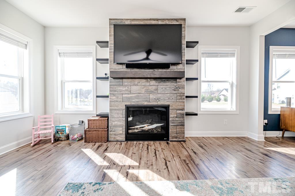 6712 Lucado Court Raleigh, NC 27603 - Photo 22 of 52 a living room with a fireplace and a floor to ceiling window
